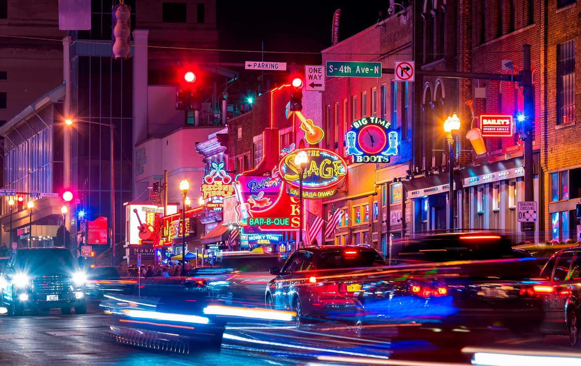 A city street at night with a lot of traffic and neon signs