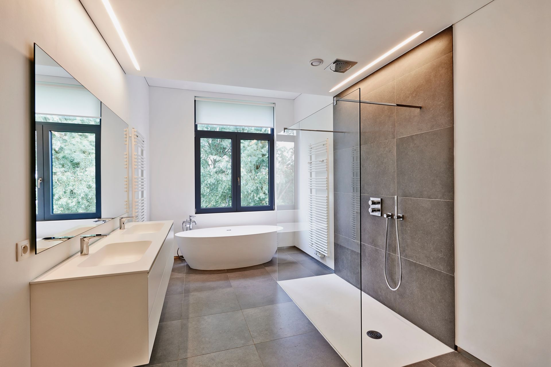 Modern bathroom with a double vanity, a freestanding white tub near a window, and a glass-enclosed walk-in shower.