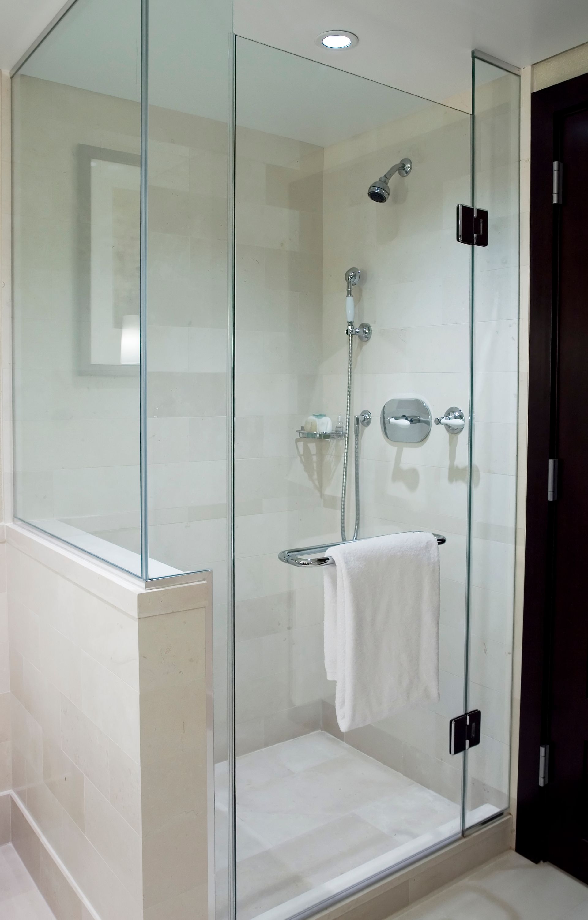 Glass shower enclosure with white towel on a towel bar.
