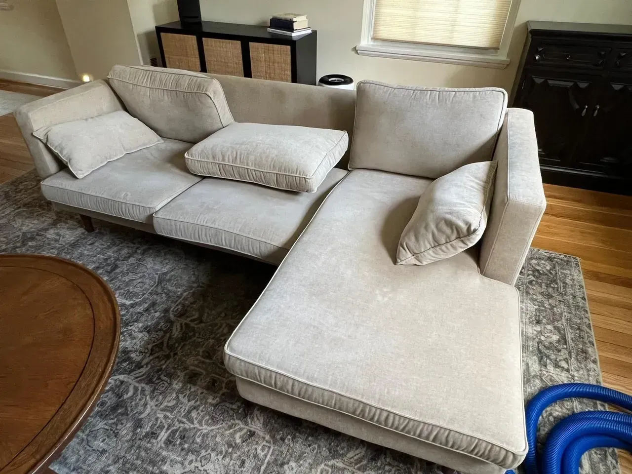 A white sectional couch is sitting in a living room next to a wooden table.