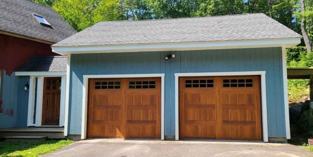 Blue garage with two brown garage doors and a brown entry door, gray roof.