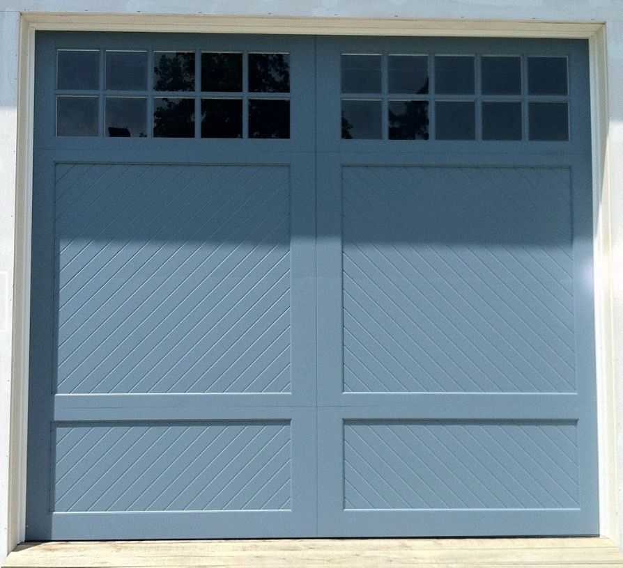 Blue garage door with windowed panels, diagonal texture, and white trim.