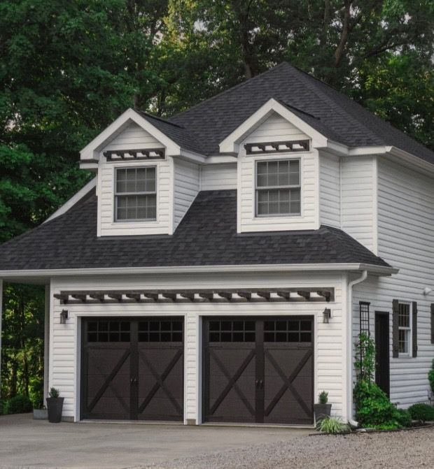 White two-story house with dark brown garage doors, two dormers, and dark trim.
