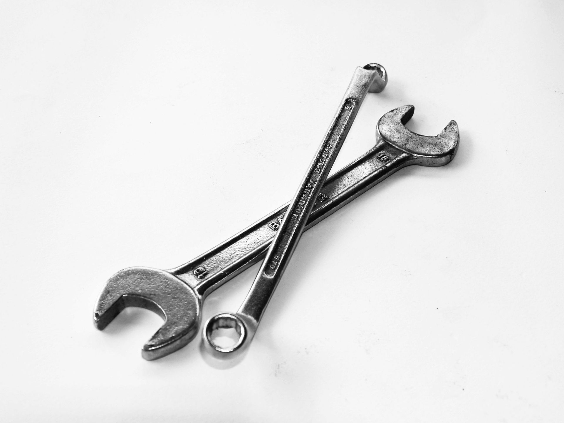 Two metal wrenches, crossed, on a white surface.