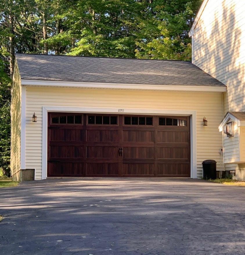 Tan garage with brown garage door, set on asphalt driveway.