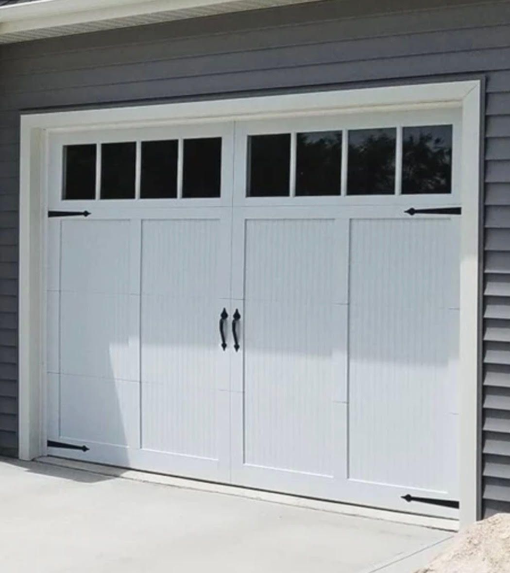 White garage door with rectangular windows, black hardware, and a gray exterior.