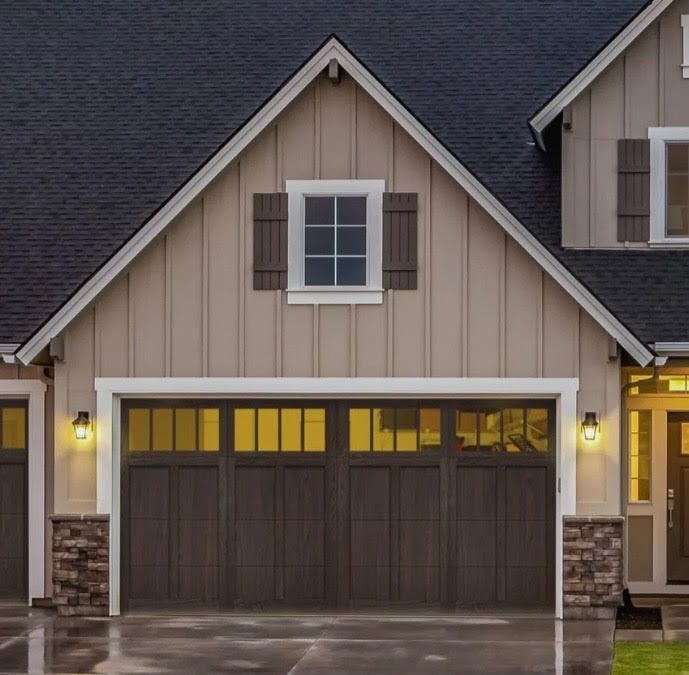 Tan house with brown garage doors and shutters, stone accents, and a dark roof.