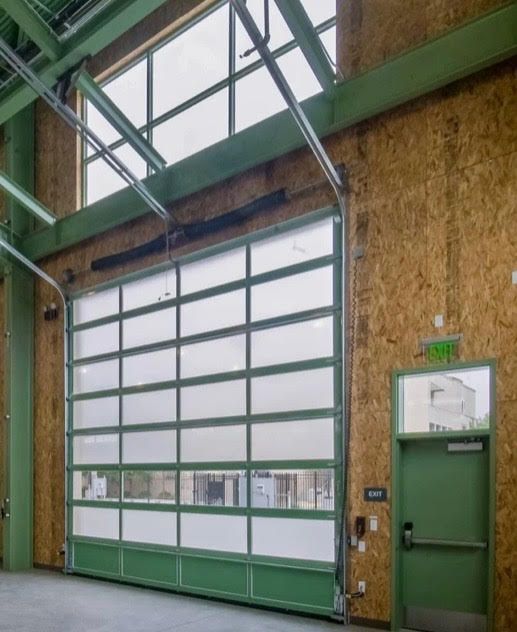 Green garage door with frosted panels, interior view. Wooden wall and green trim.