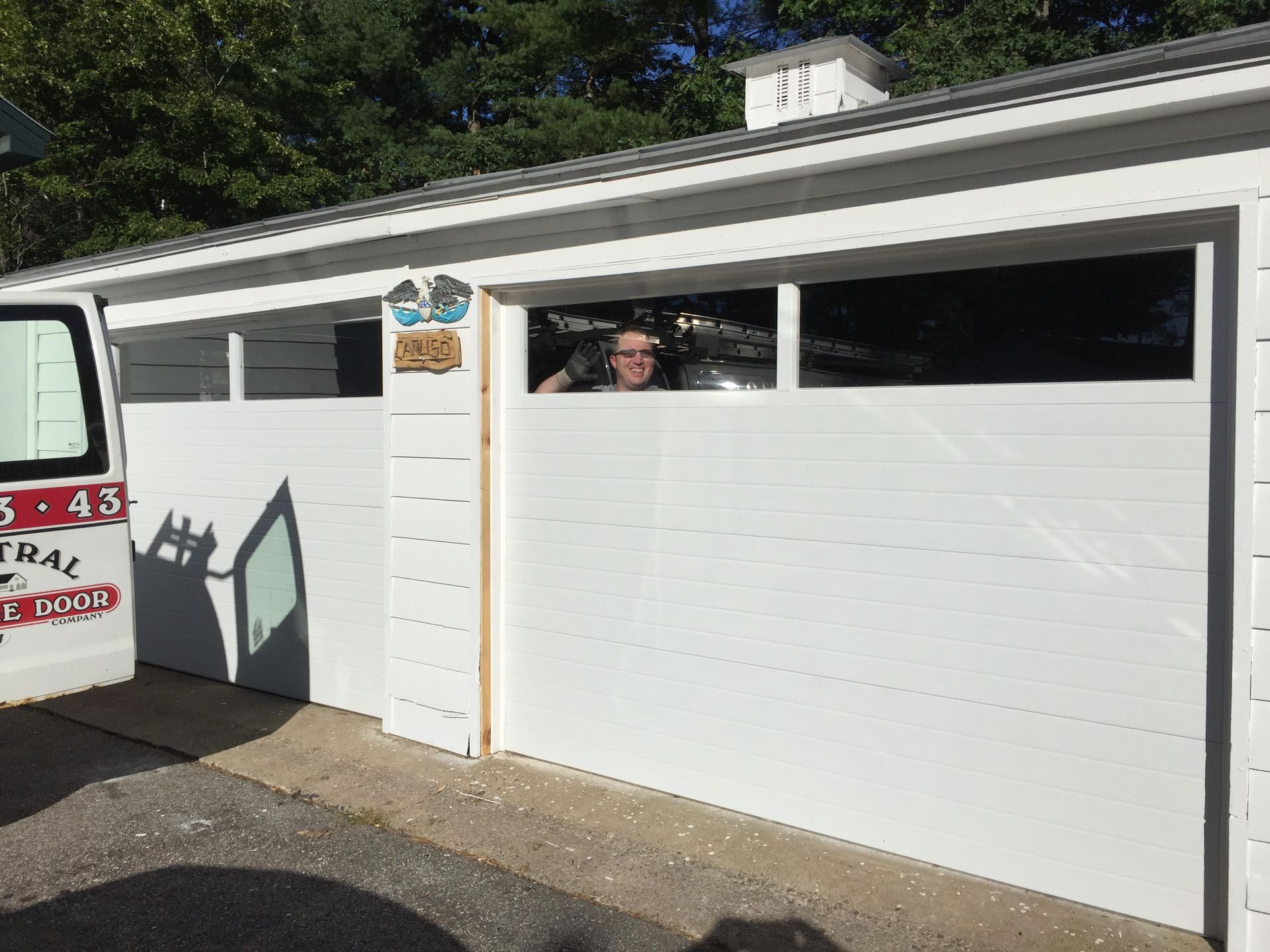 White garage doors; person peeking from window; service van parked nearby.