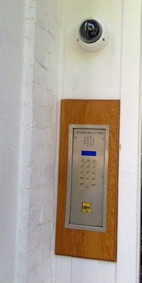 a security camera is mounted on the side of a building next to a keypad .