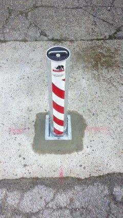 a red and white pole is sitting on the side of a road .