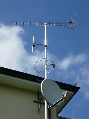 an antenna and satellite dish on the roof of a house .