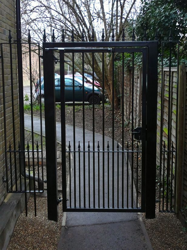 a black wrought iron gate leading to a parking lot