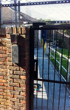 a black gate with a brick wall behind it