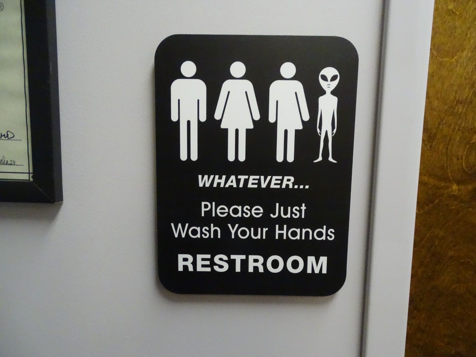 All gender friendly restroom sign with three people and an alien that says