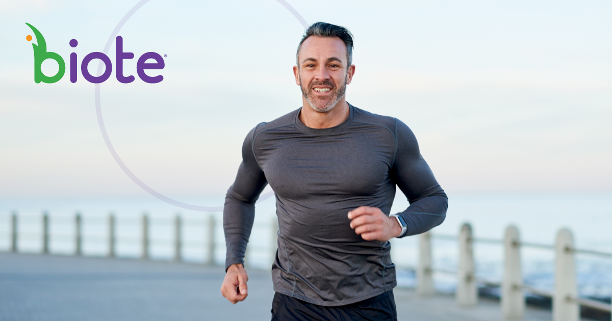 A man is running on a beach next to the ocean.