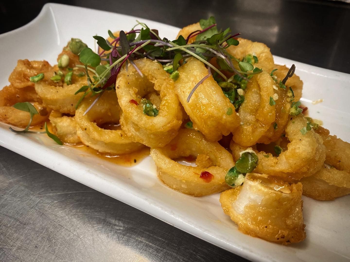 A white plate topped with fried calamari on a table.