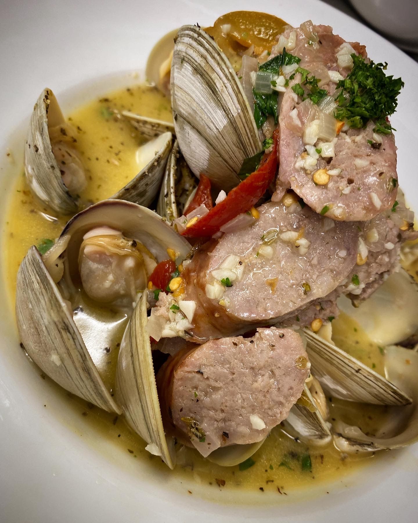 A white plate topped with clams , meat and sauce