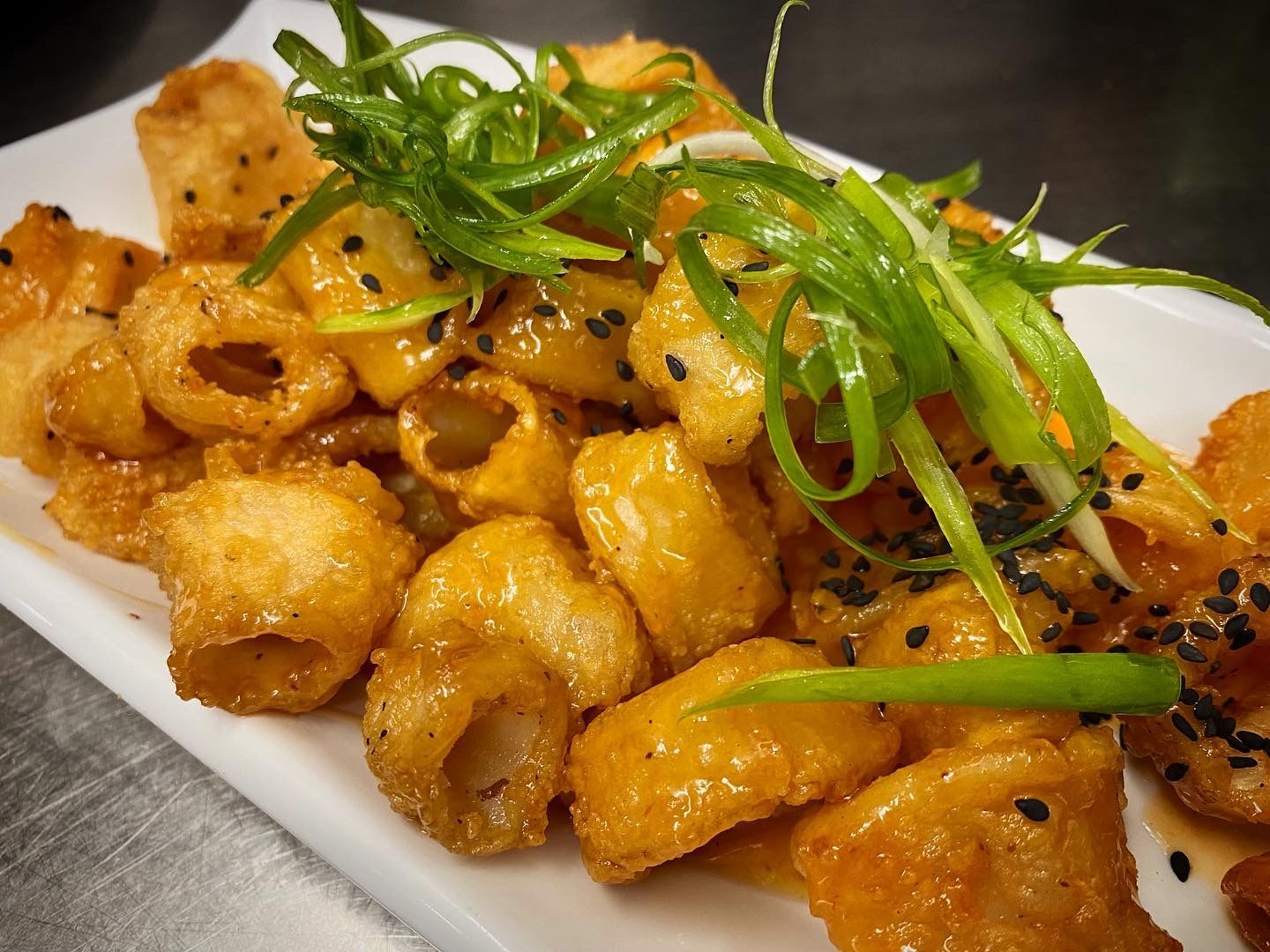 A white plate topped with fried food and green onions.