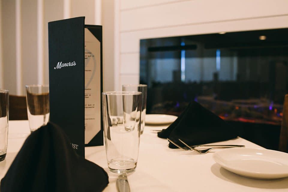 A restaurant table with plates , glasses , and a menu on it.