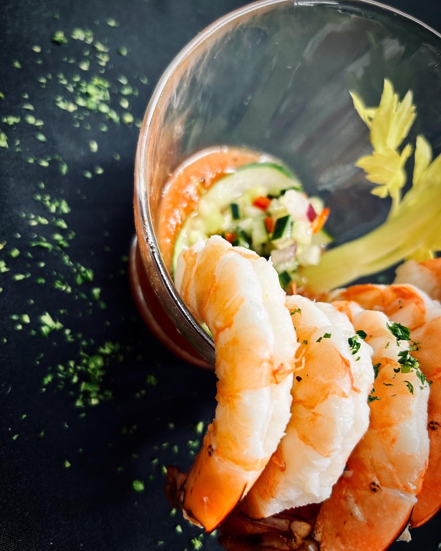 A glass filled with shrimp and vegetables on a table