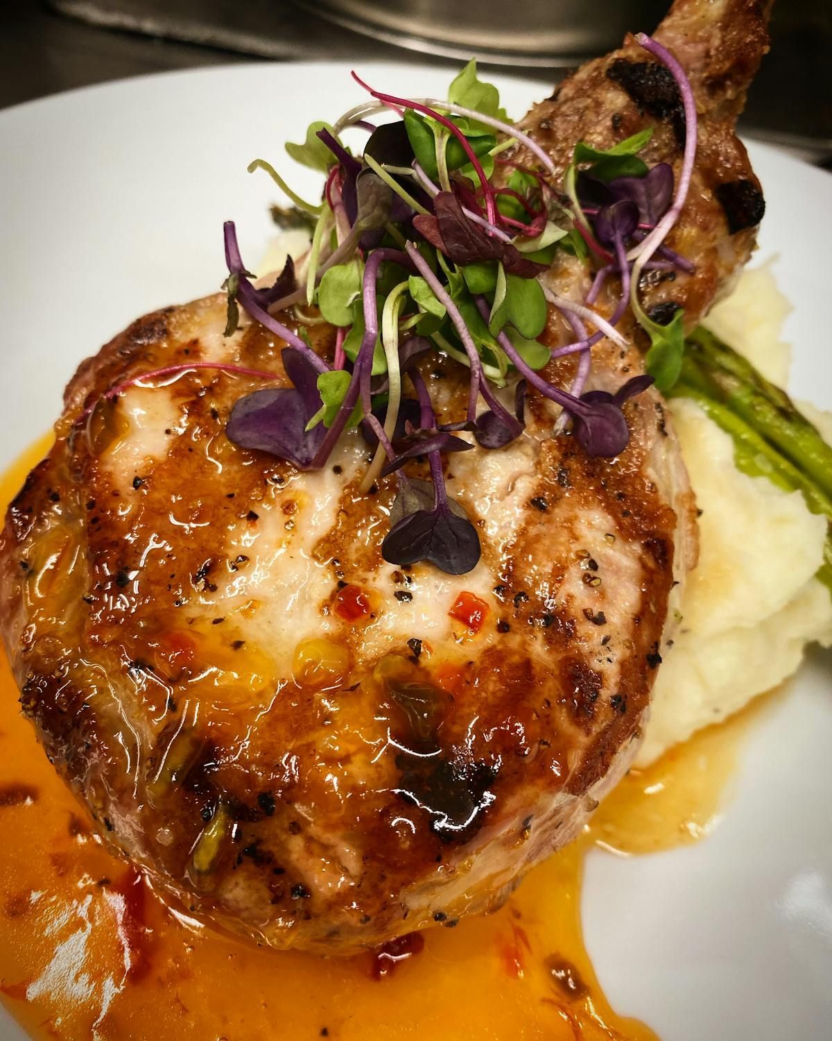 A white plate topped with a piece of meat and mashed potatoes.