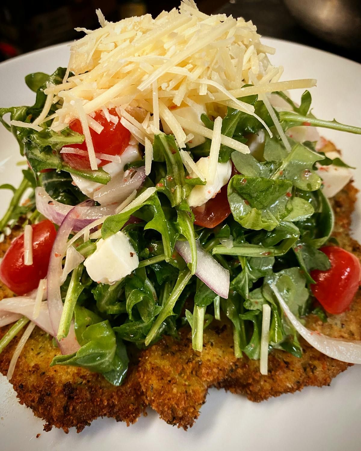 A close up of a plate of food with vegetables and cheese on top.