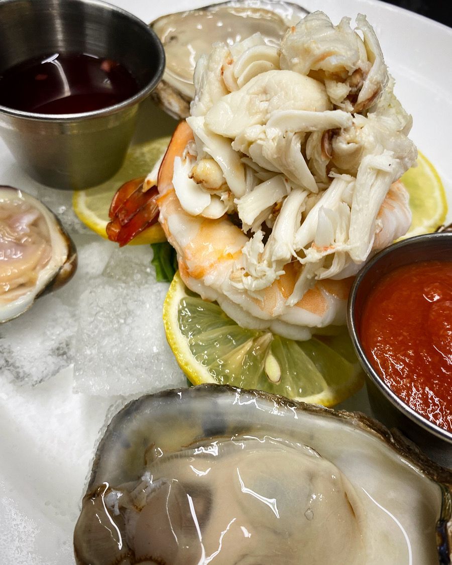 A white plate topped with oysters shrimp and crab