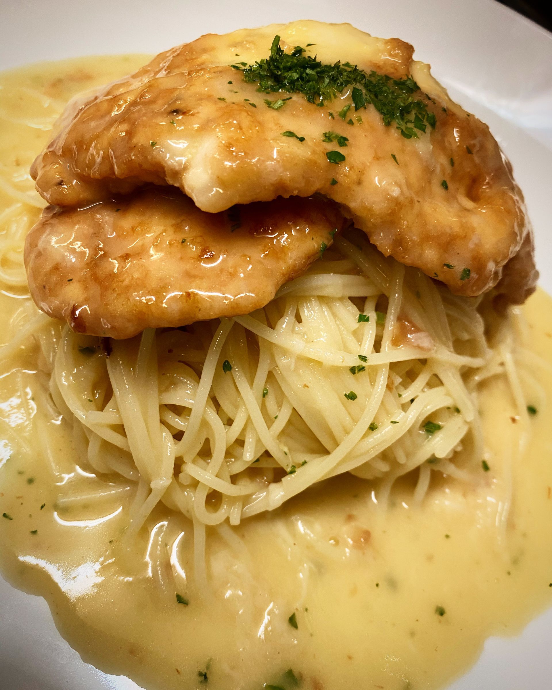 A close up of a plate of food with noodles and chicken on a table.