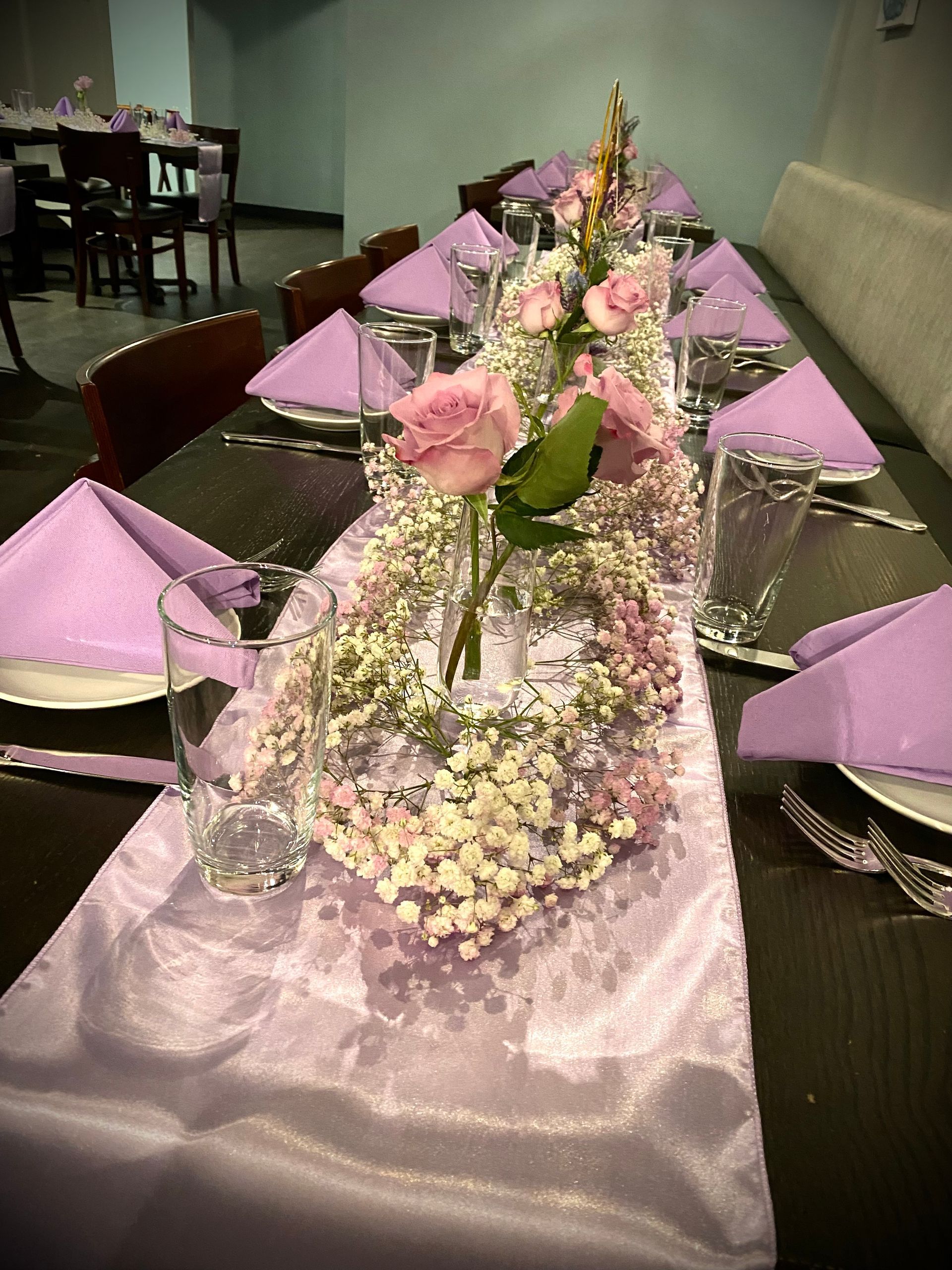A long table with purple napkins and flowers on it