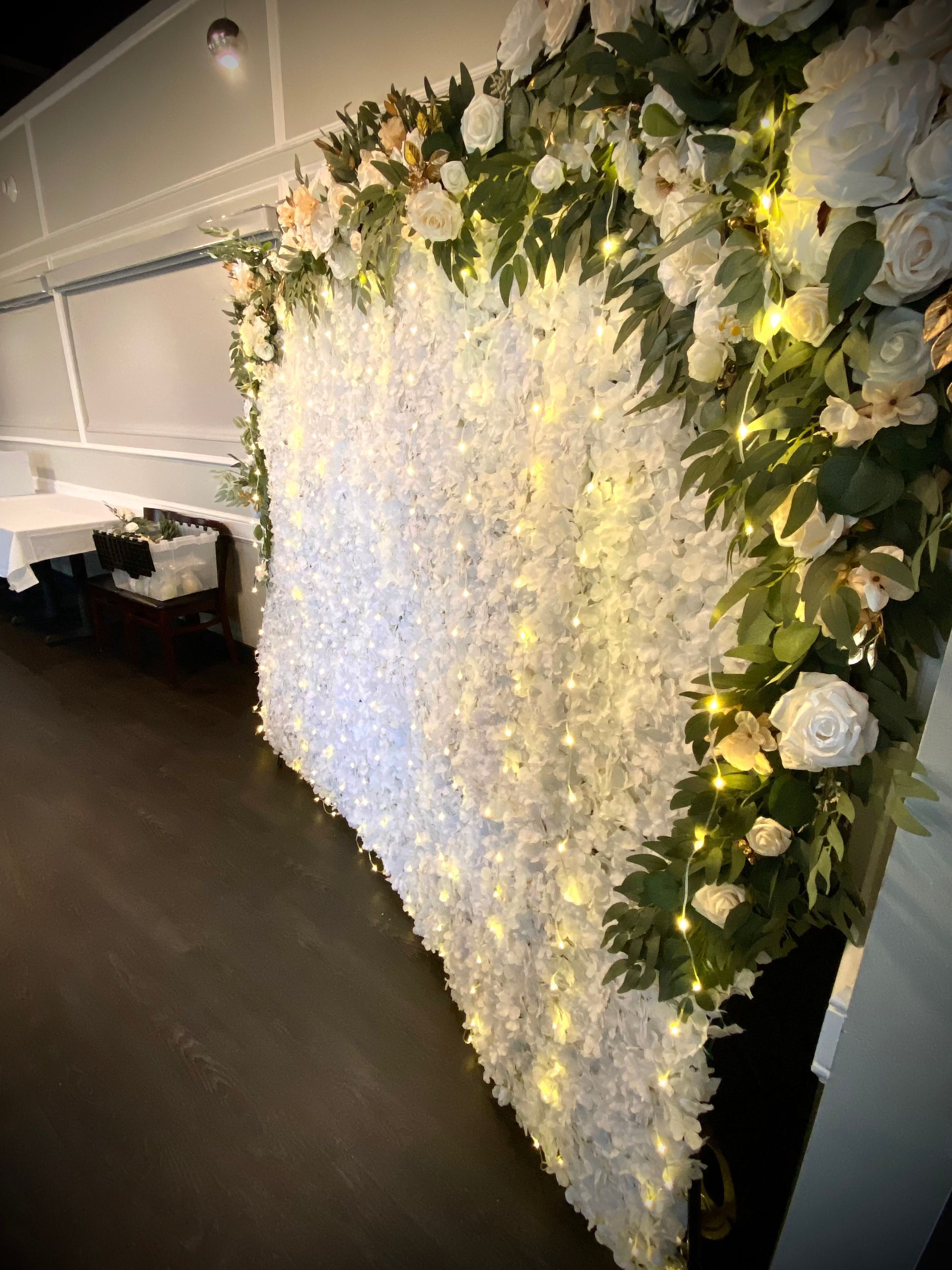 A white wall with flowers and lights on it in a room.