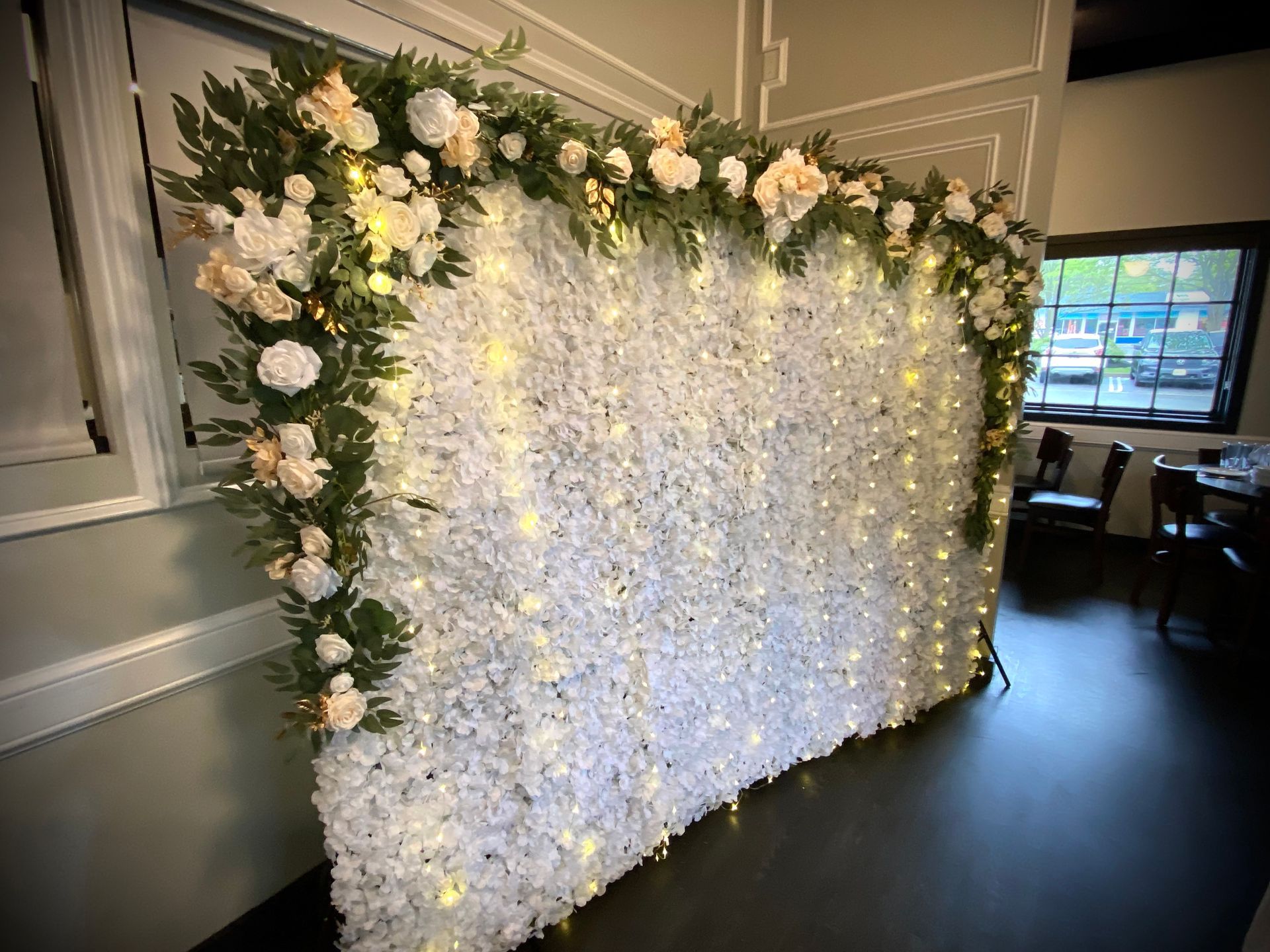 A wall of white flowers and lights in a room.