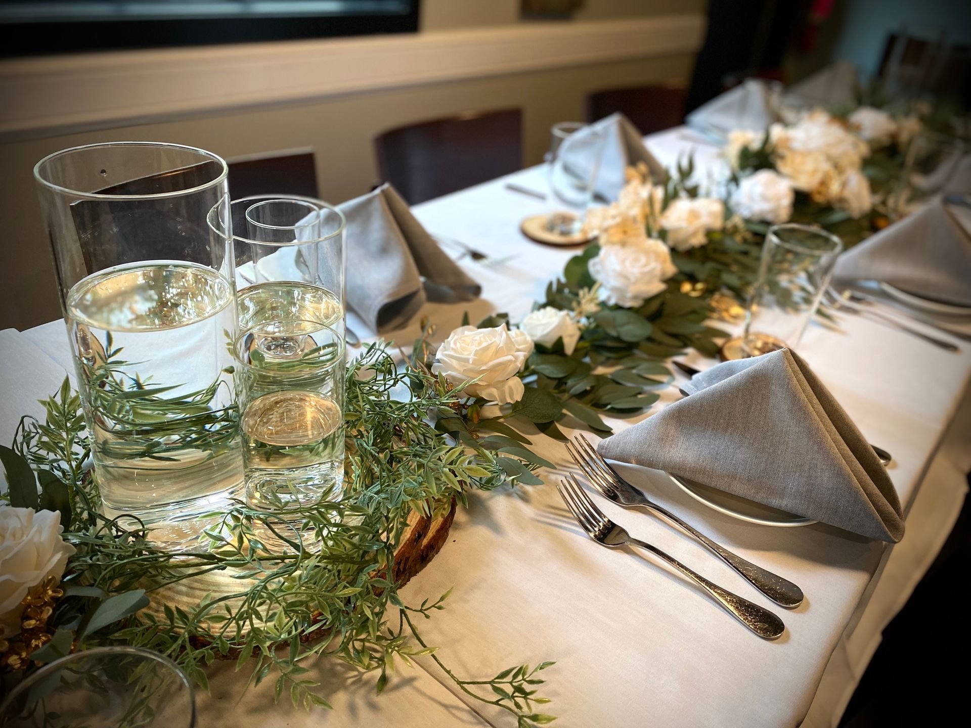 A long table with a vase of water and flowers on it.
