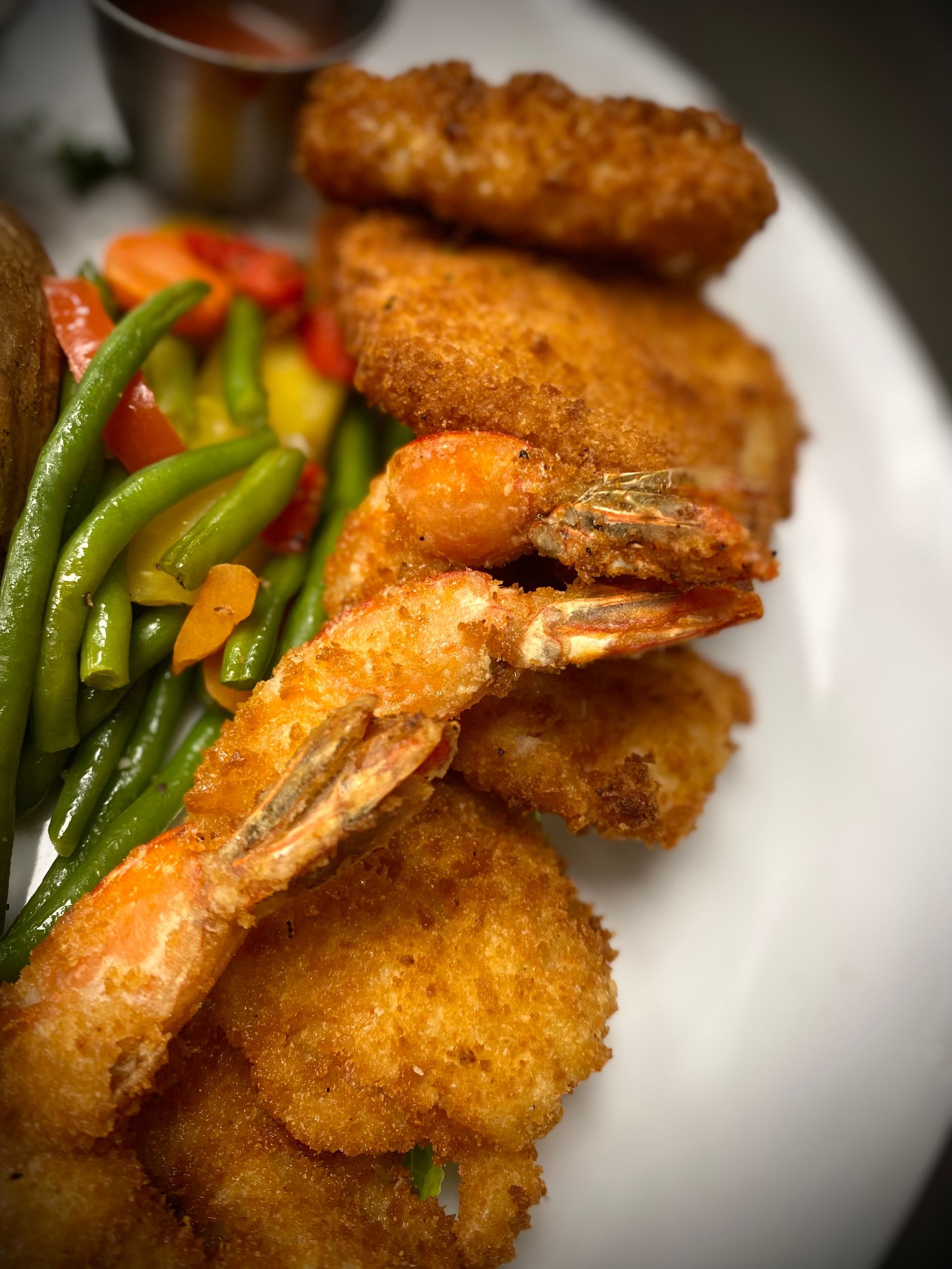 A close up of a plate of food with shrimp and green beans on a table.