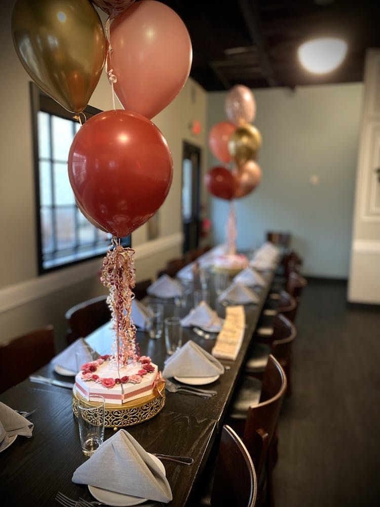 A long table with a cake and balloons on it.