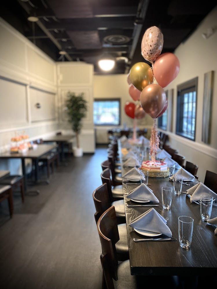 A restaurant with tables and chairs and balloons hanging from the ceiling