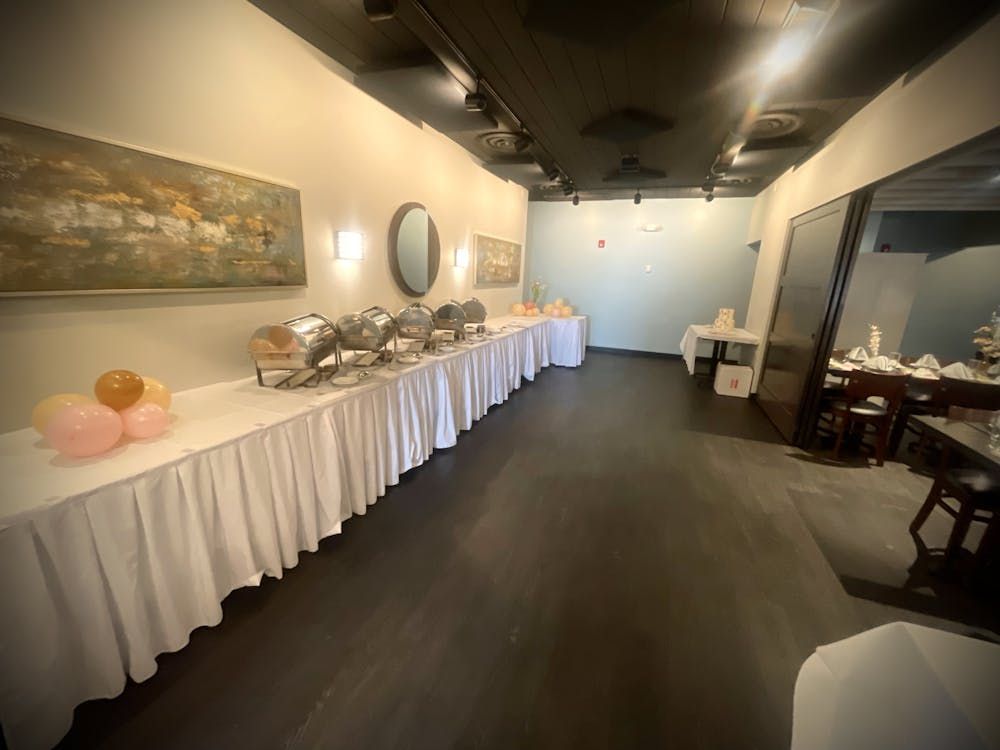 A long room with a lot of tables and balloons on them.