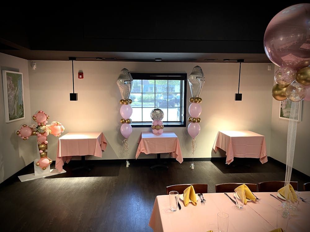 A room with tables and chairs and balloons on the wall.