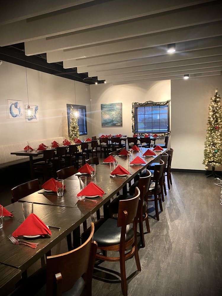 A dining room with tables and chairs and a christmas tree.