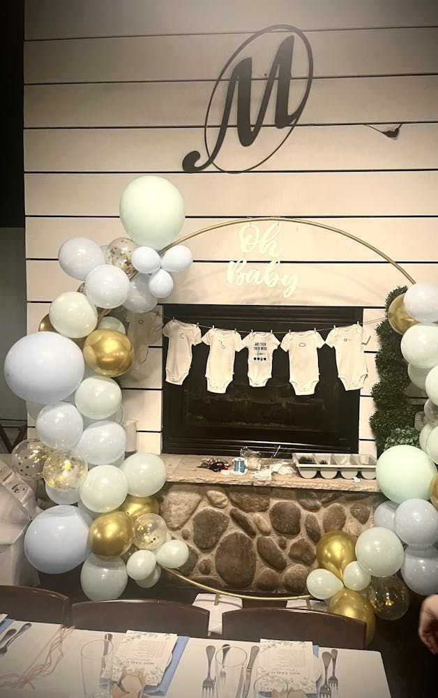 A fireplace decorated with balloons and a banner for a baby shower.
