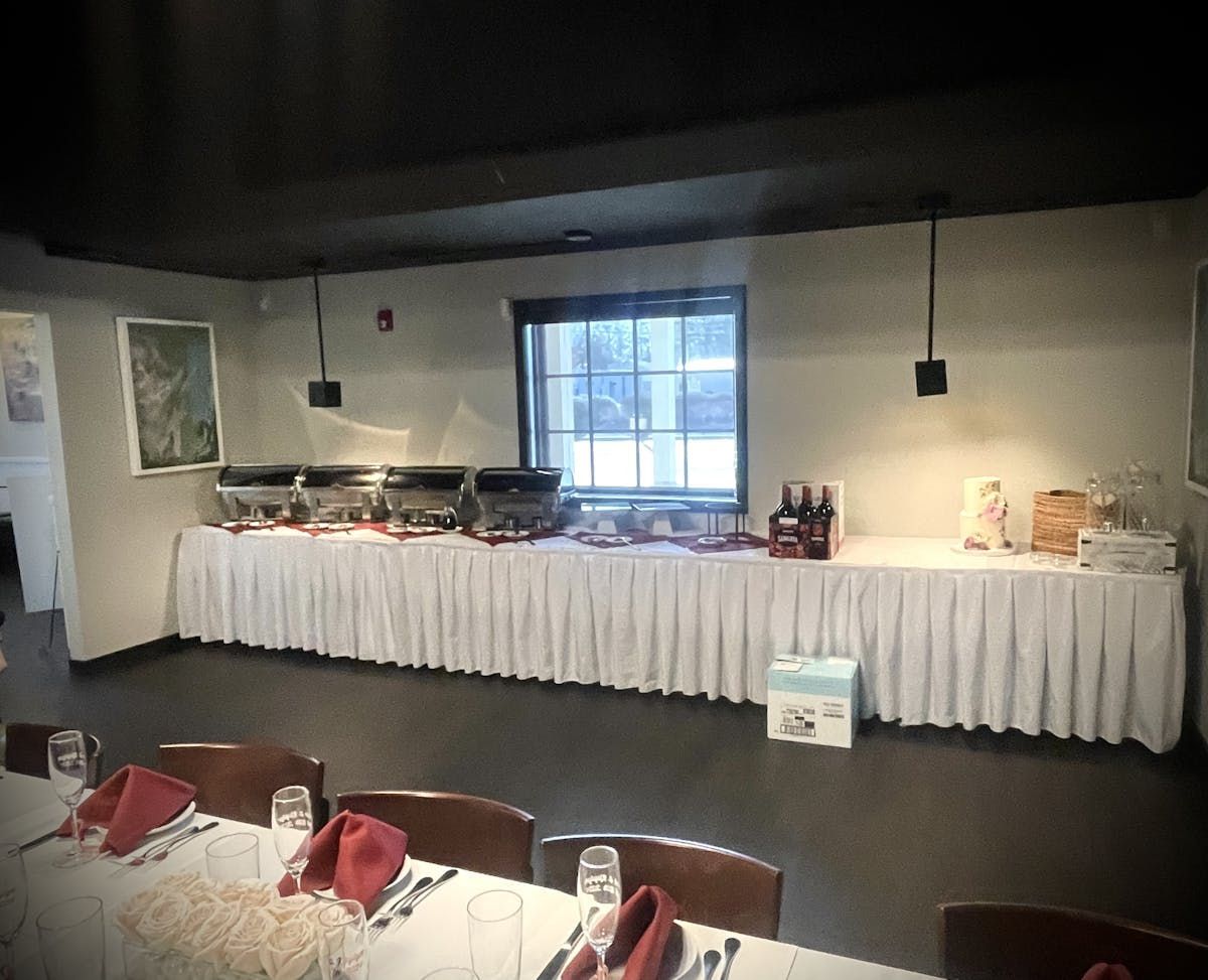 A long table with a white table cloth and a window in the background
