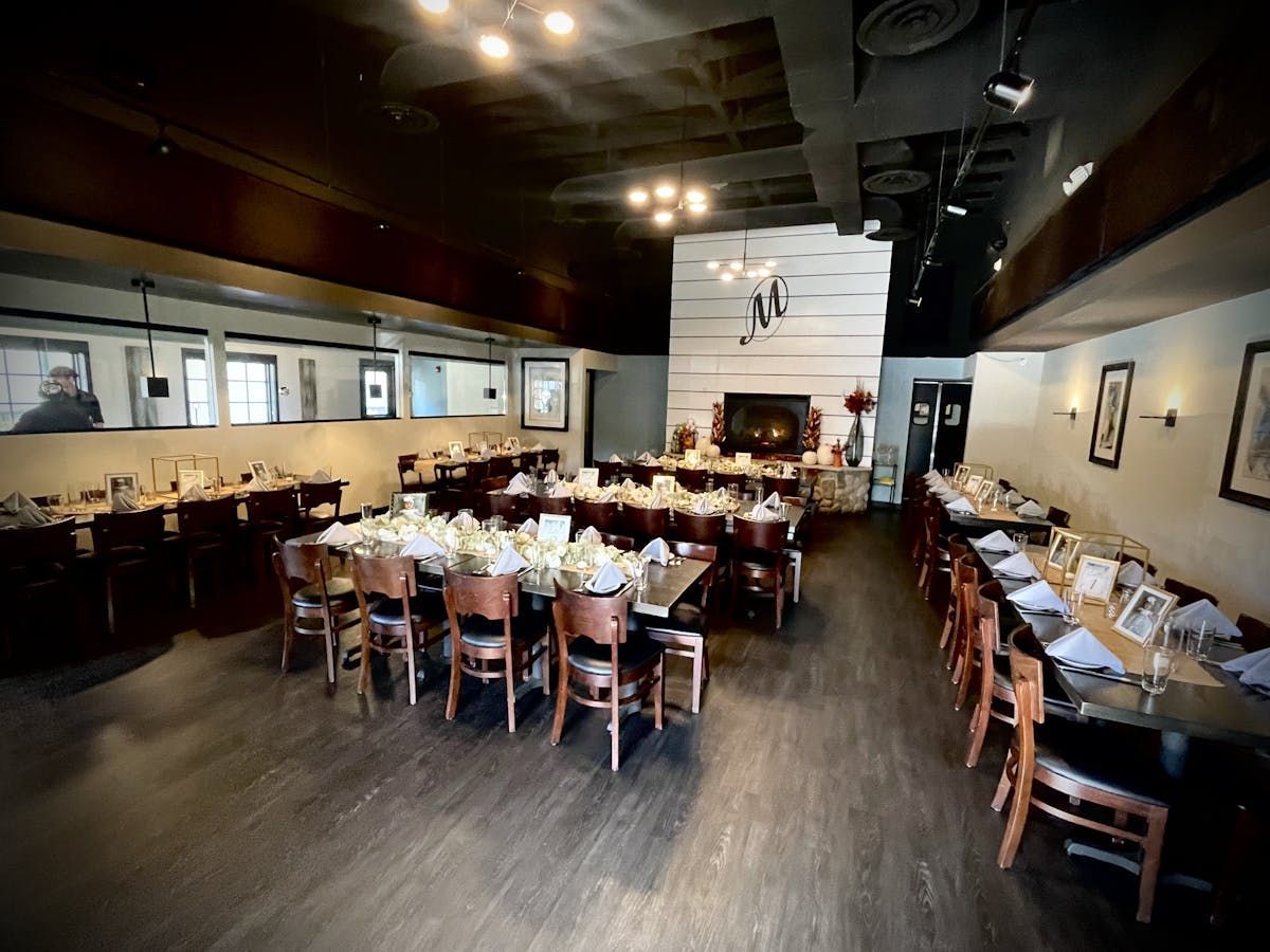 A large dining room with tables and chairs and a fireplace.