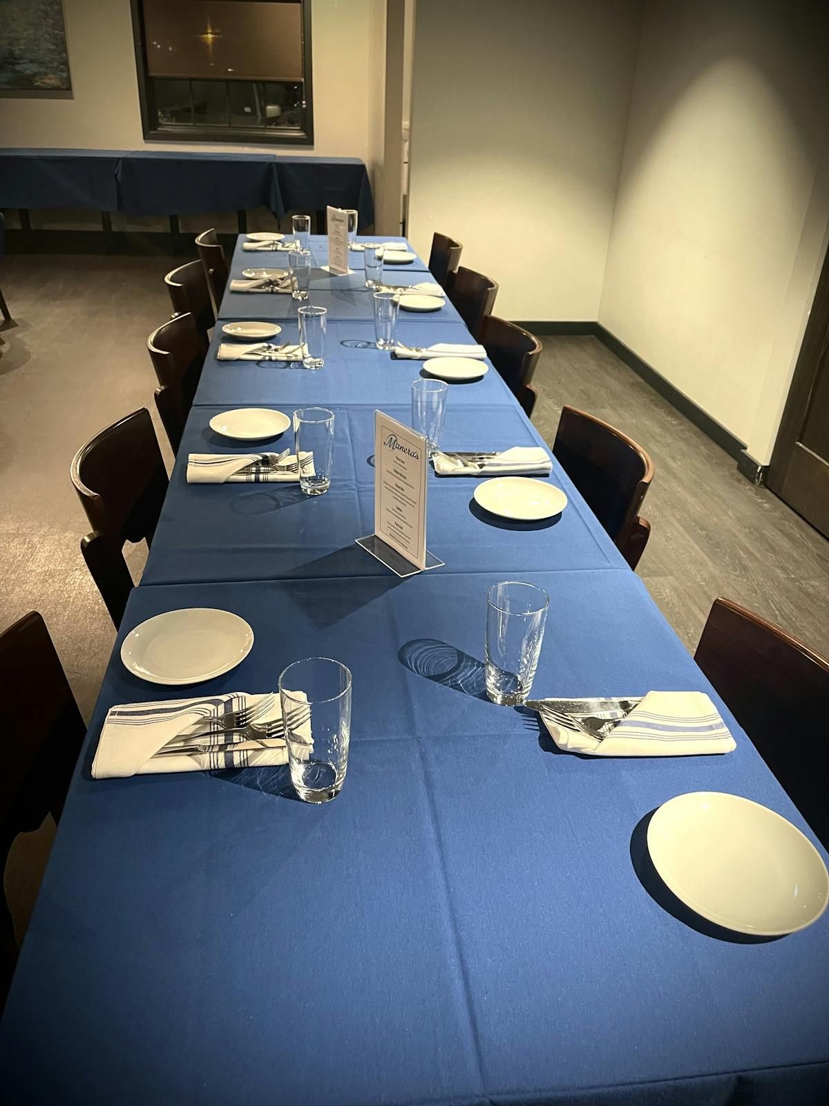 A long table with plates , glasses and napkins on it