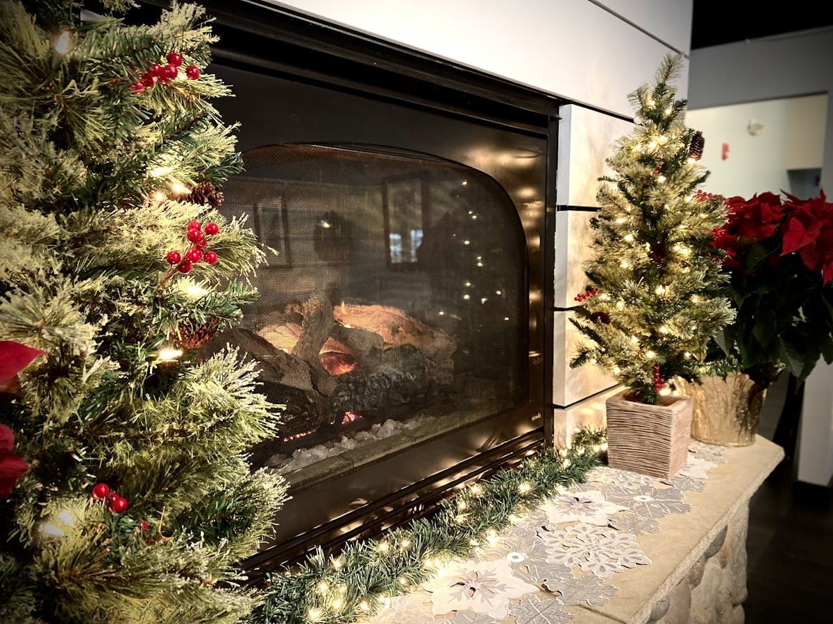 A fireplace decorated for christmas with trees and lights