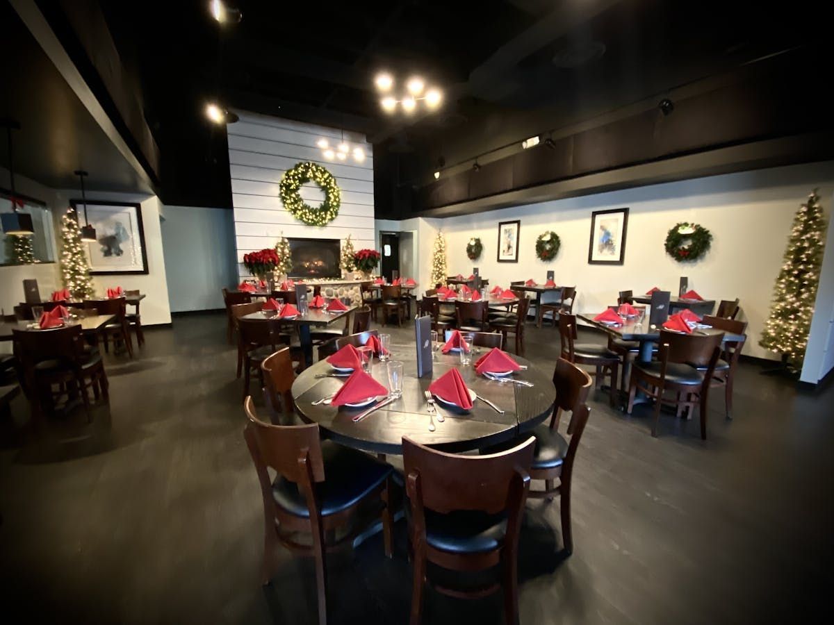 A large dining room with tables and chairs and a fireplace.