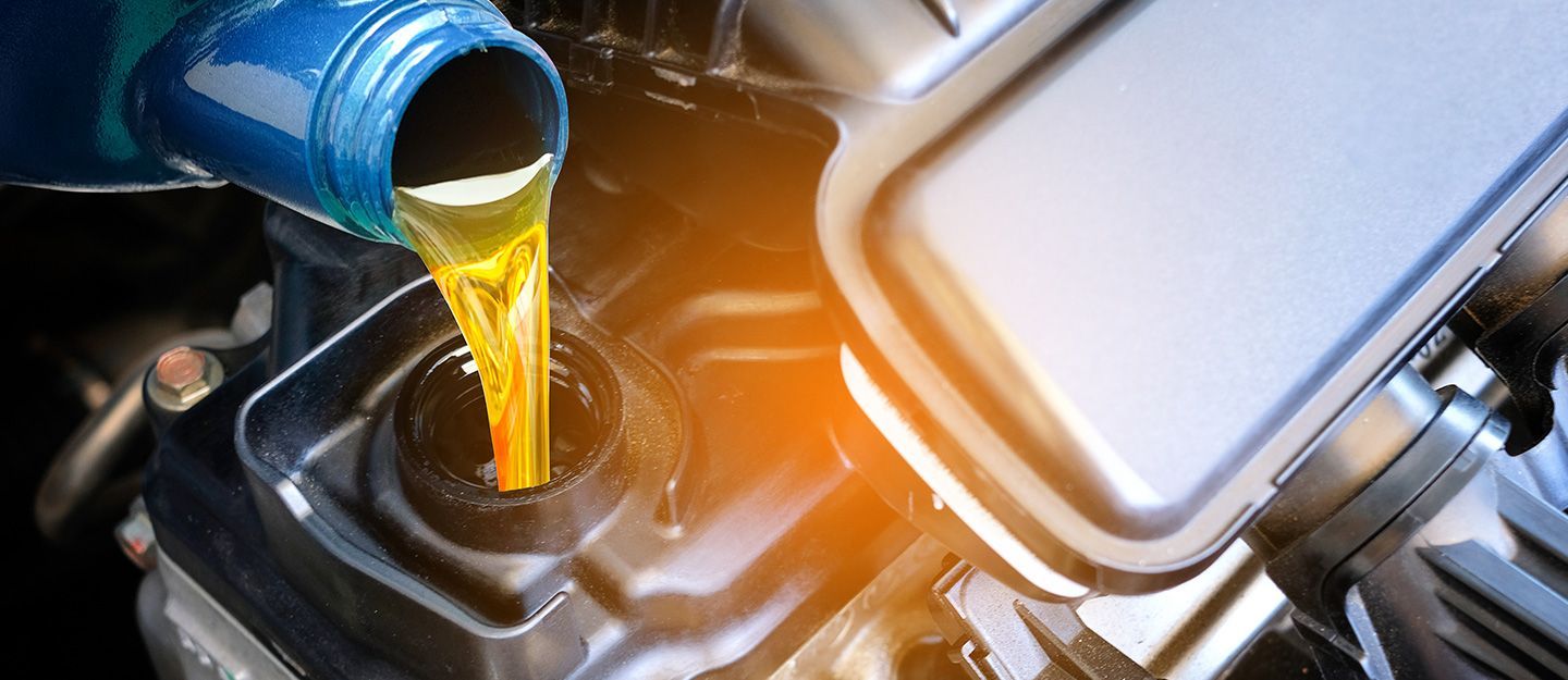 A close up of a person pouring oil into a car engine | B&B Automotive Services