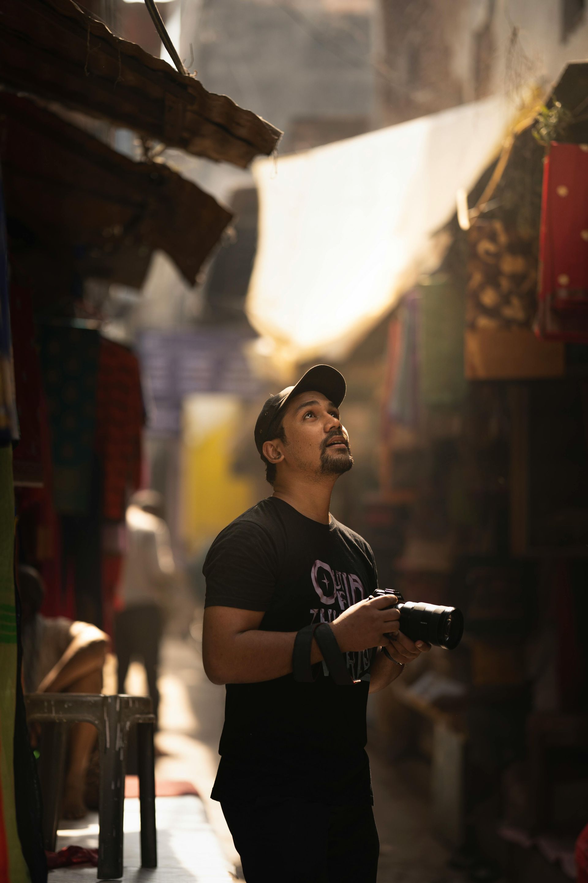 A man is standing in a narrow alleyway holding a camera.