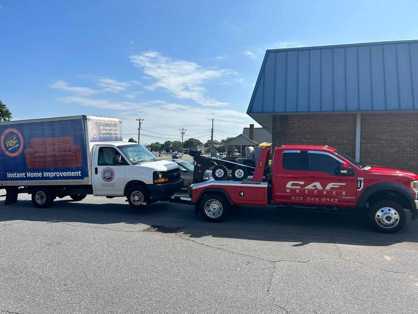 Two tow trucks are parked next to each other in front of a building.