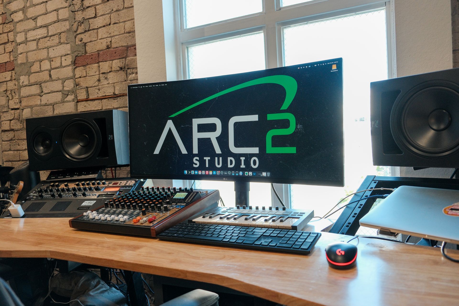 A computer monitor is sitting on a wooden desk in a studio.