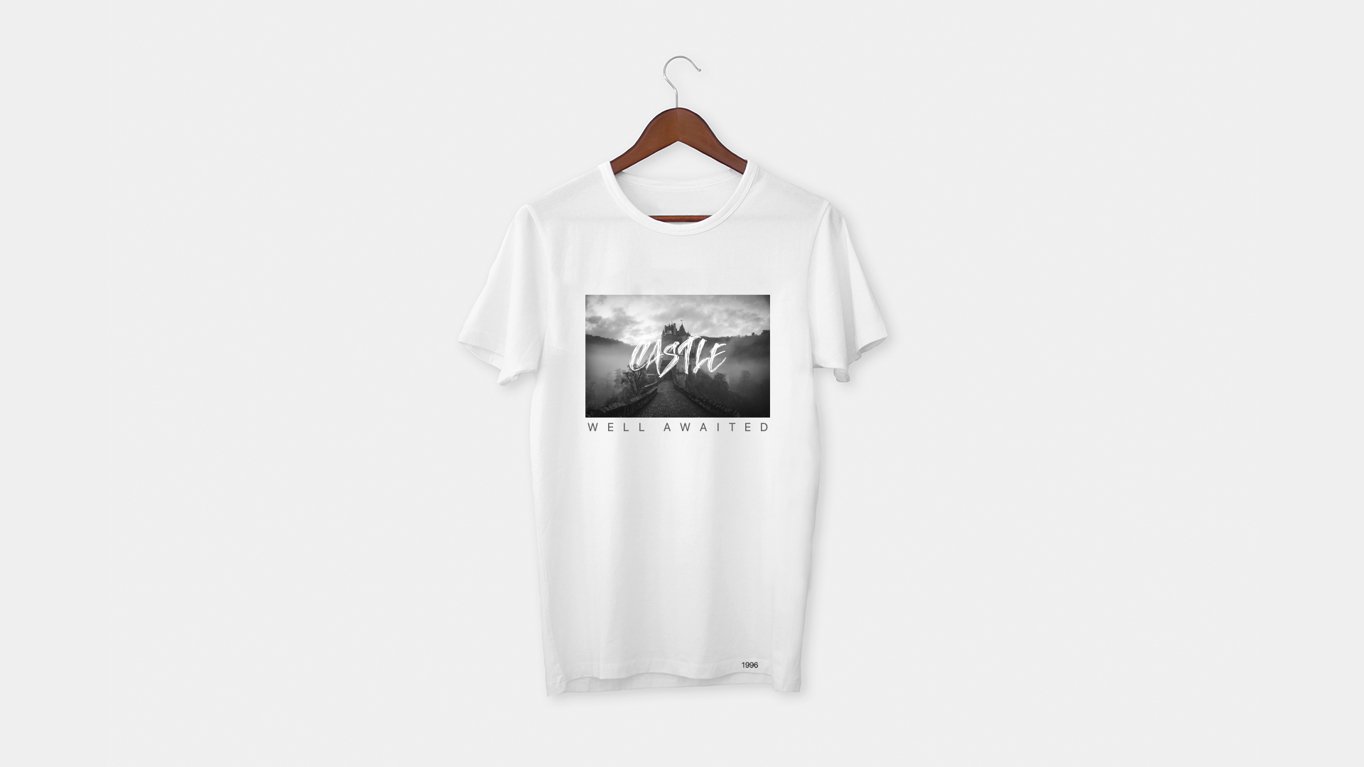 A white t-shirt is hanging on a wooden hanger.